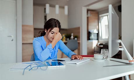 A woman in a blue top stressed at her office desk
