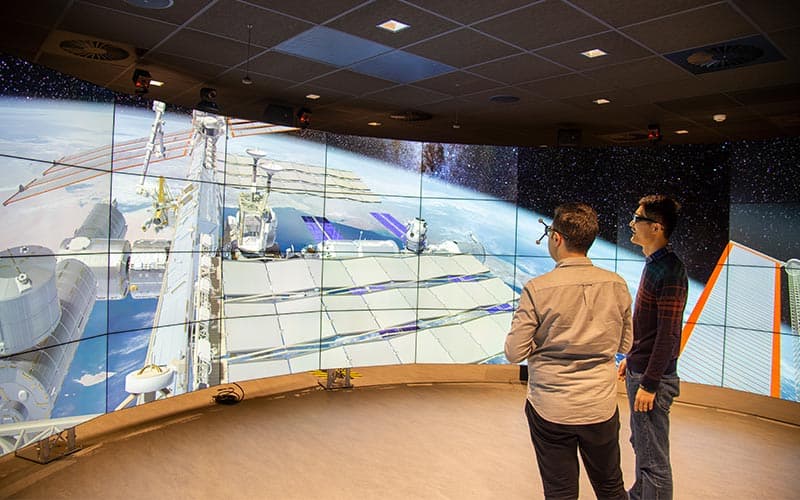Two students surveying the view of the Data Visualisation Observatory's International Space Station