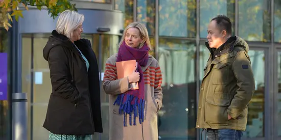 Three AMBS colleagues stood outside the school building having a conversation