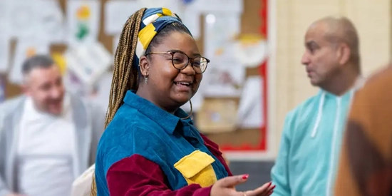 A woman adviser greeting a group of adults in a community centre