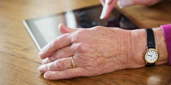 Older woman's hands using a digital tablet