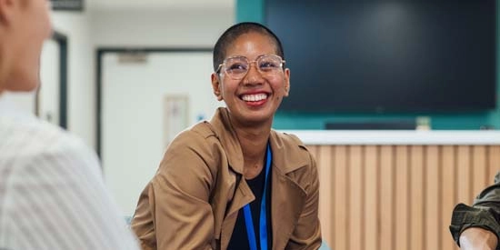 A professional young woman sitting in an office smiling at her co workers