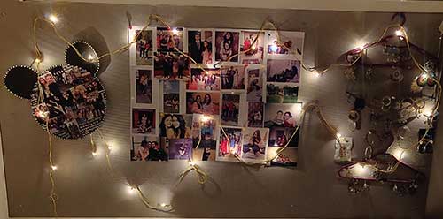 Photos on a wall surrounded by fairy lights