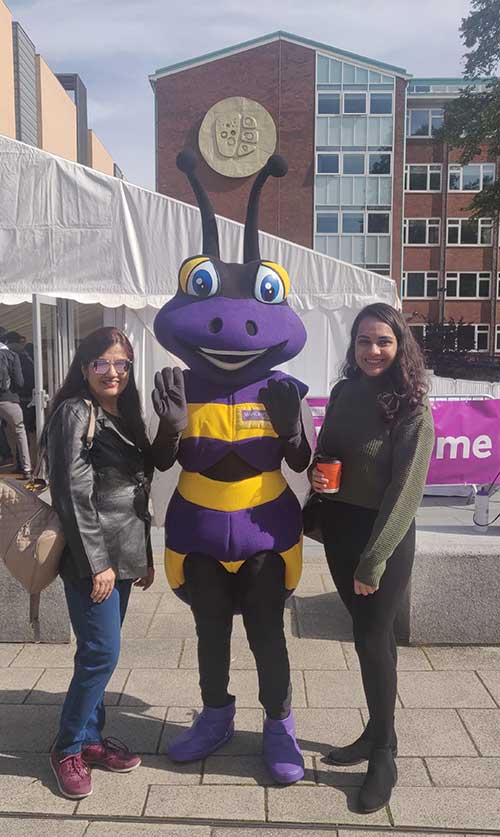 Payal Mehta and a friend standing with someone in a bee costume at a Welcome Week event