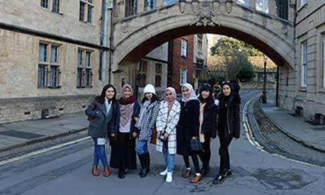 Amanda Kusmajaya with a group of her student friends standing near a stone arch