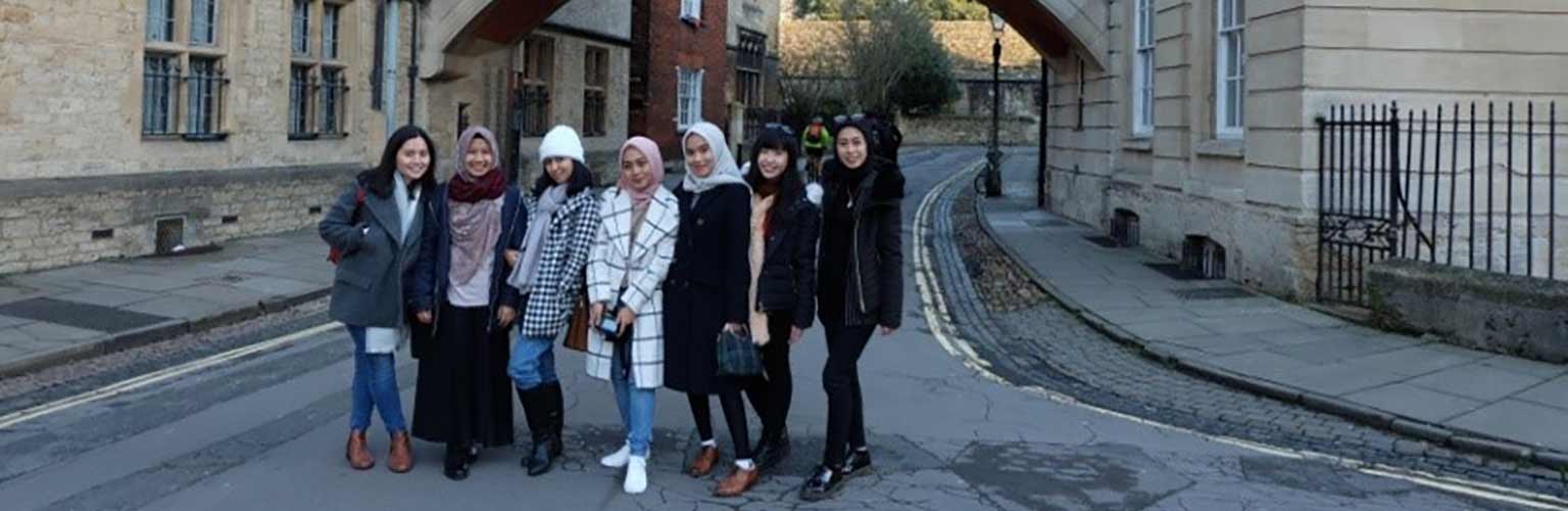 Amanda Kusmajaya with a group of her student friends standing near a stone arch