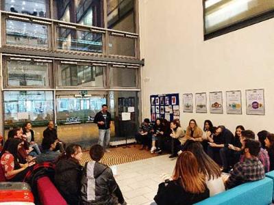 A group of students sat surrounding somebody speaking