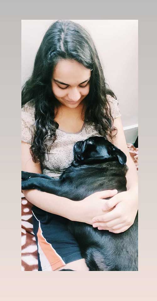 Payal Mehta hugging a black dog