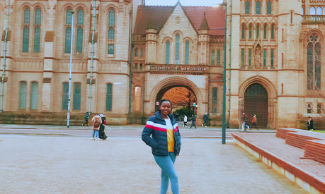 Emerance Mutesi at Brunswick Park with The University of Manchester in the background. 