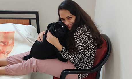 Payal Mehta hugging a black dog