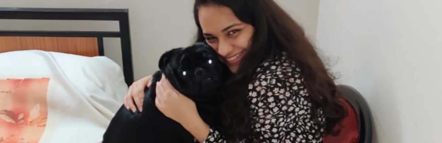 Payal Mehta hugging a black dog