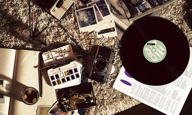 a record, a camera and a painting set on a table