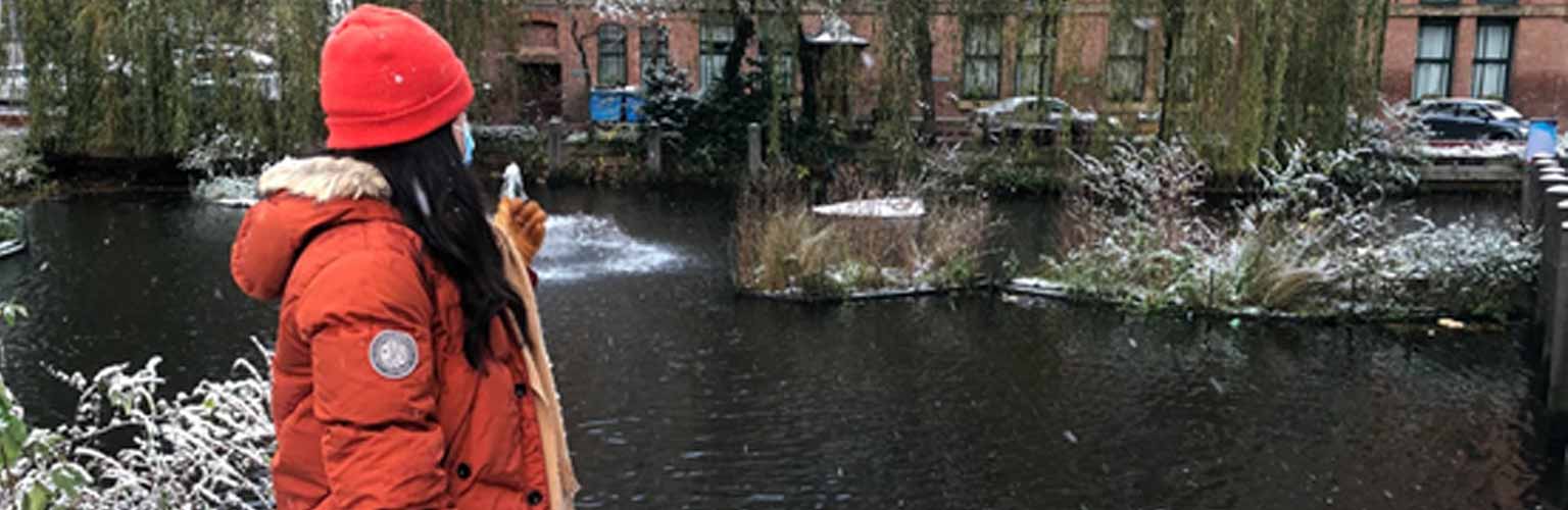 student looking over winter river in manchester