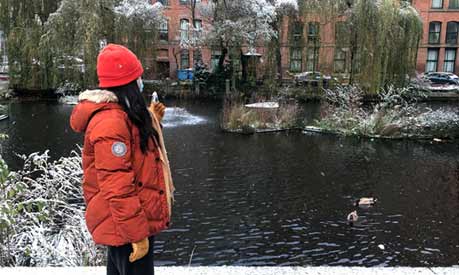 student looking over winter river in manchester