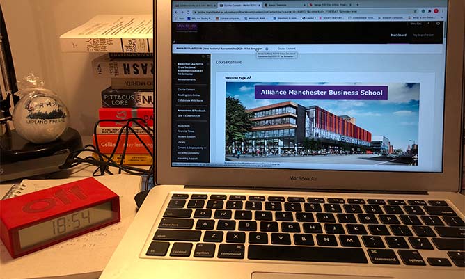 A laptop with a presentation featuring the Alliance Manchester Business School building on