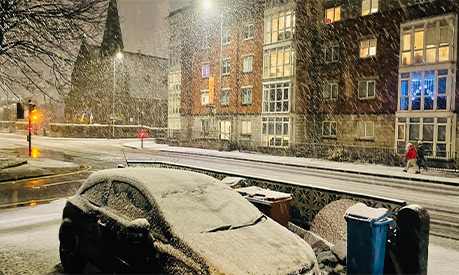 A snow covered street with a church in the background 