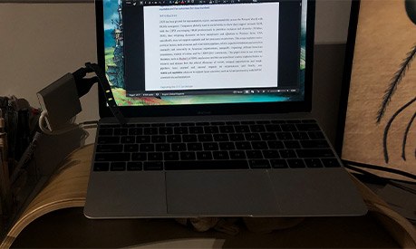 A wooden desk with a laptop on and a water bottle to the left of it