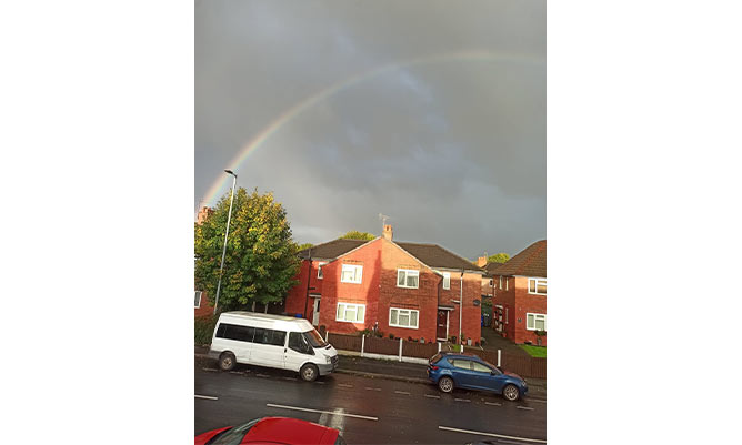 A house in the UK with overcast skies and a rainbow