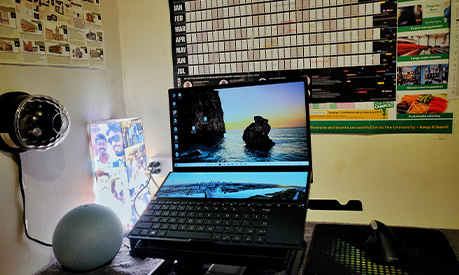 A desk with a laptop on with a calendar in the background