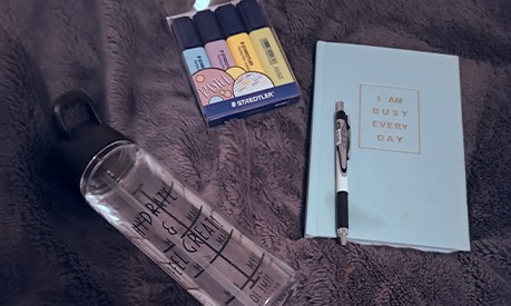 A notepad, a water bottle and a pack of highlighter pens