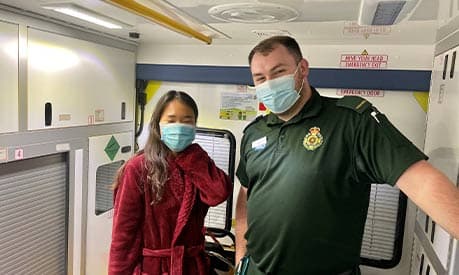 Victoria Kim with a paramedic inside an ambulance with a face covering on