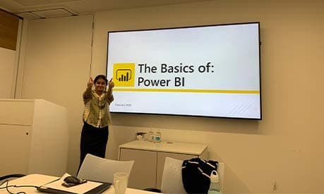 Palak giving two thumbs up with a presentation titled 'The Basics of: Power BI' in the background