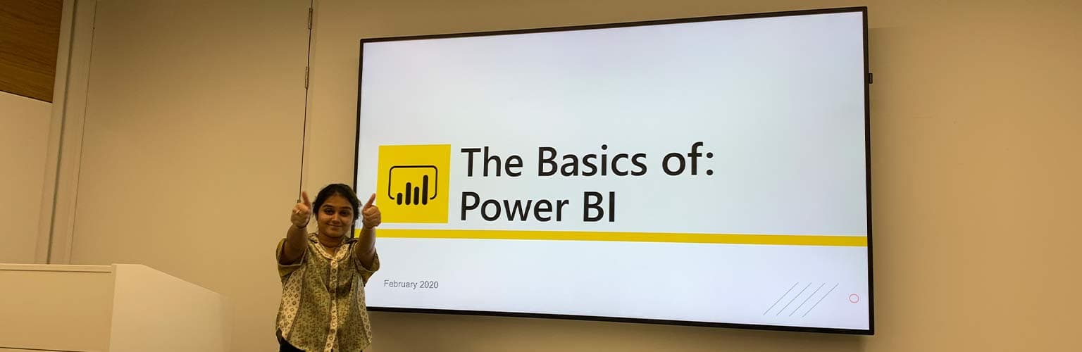 Palak giving two thumbs up with a presentation titled 'The Basics of: Power BI' in the background