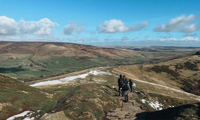 A view of some hikers in the Peak District during a sunny day