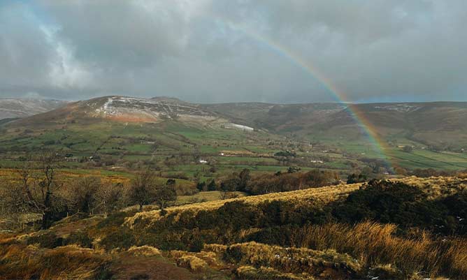 A rainbow that can be seen through the clouds in the Peak District