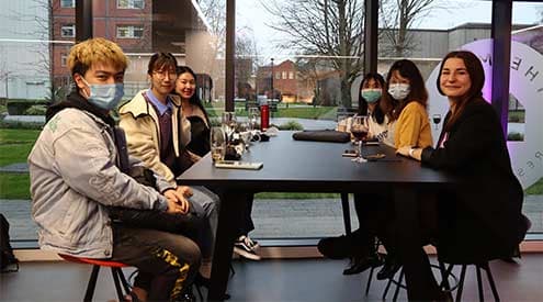 Eleni Chliapa and her friends sitting around a table in The Mill Restaurant at the Alliance Manchester Business School