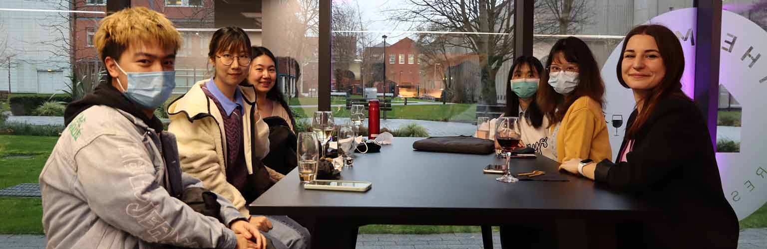 Eleni Chliapa and her friends sitting around a table in The Mill Restaurant at the Alliance Manchester Business School