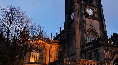 A picture of the front of a church in Manchester at dusk