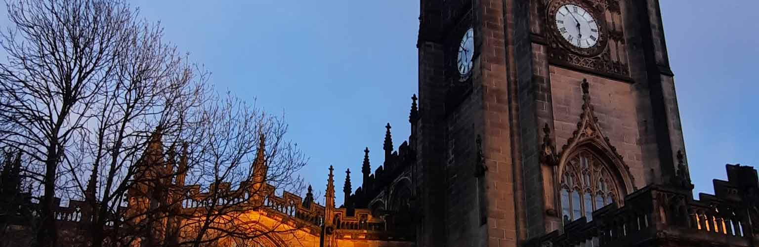 A picture of the front of a church in Manchester at dusk