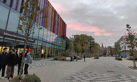 A view of the front of the Alliance Manchester Business School building during a sunset