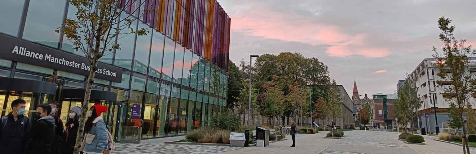 A view of the front of the Alliance Manchester Business School building during a sunset