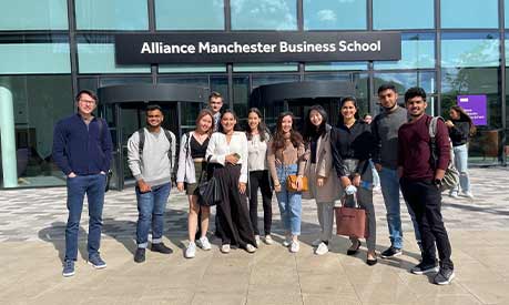 Rishwin Barasia and friends in front of the Alliance Manchester Business School building.