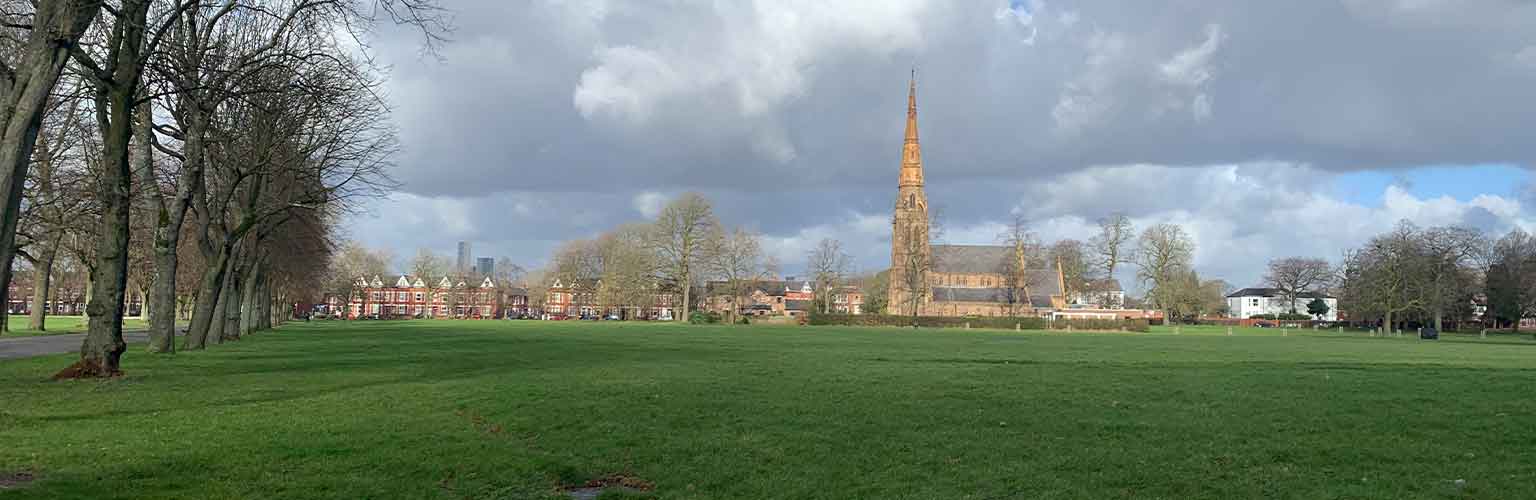 A park in Manchester with blue sky and white cumulus clouds