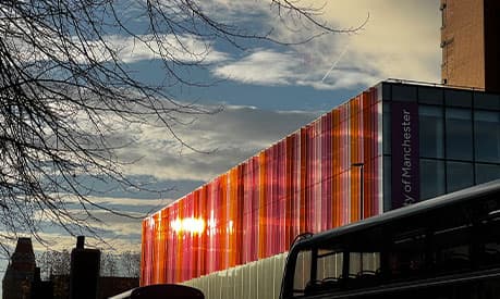 The sun reflecting off the Alliance Manchester Business School building looking down Oxford Road