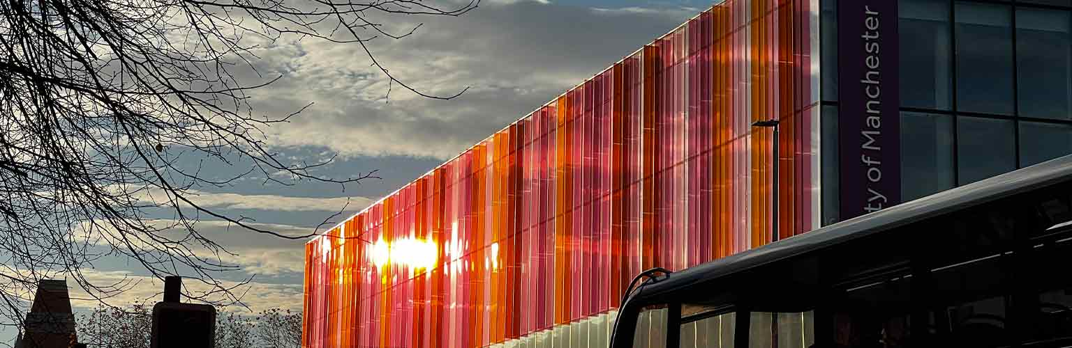 The sun reflecting off the Alliance Manchester Business School building looking down Oxford Road