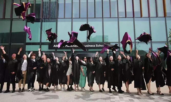 Yitong Zhang celebrating graduating with her cohort outside the Alliance Manchester Business School