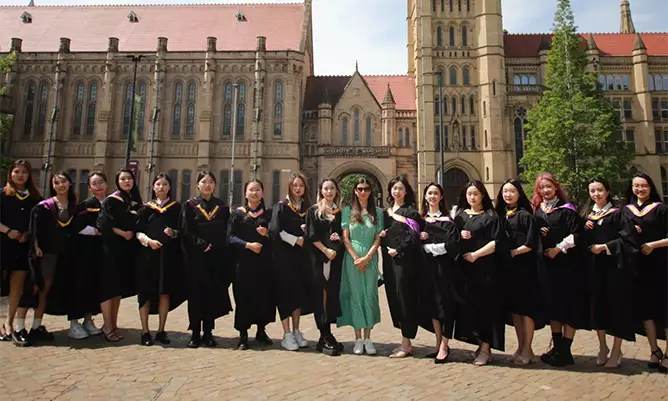 Yitong Zhang celebrating graduating with her cohort standing formally outside the University of Manchester