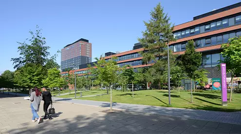 Alliance Manchester Business School's University Green in the sunshine with the Hyatt Hotel in the background