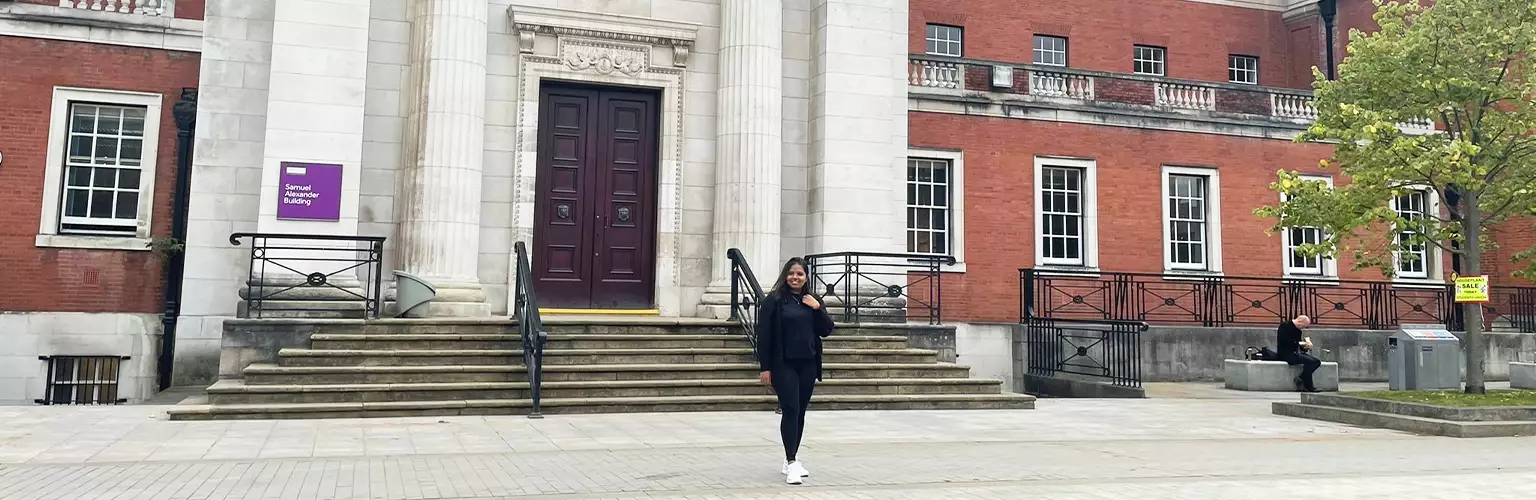Celeste Fernandes standing outside the Samuel Alexander building at The University of Manchester