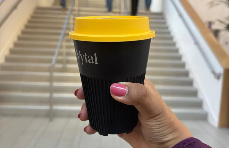 Niharika Singh, a student at Alliance Manchester Business School, holding a reusable coffee cup inside the Alliance MBS building.