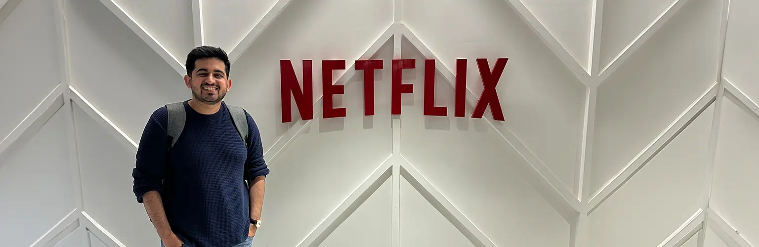 Armaan Raj Dua standing next to a large Netflix logo.