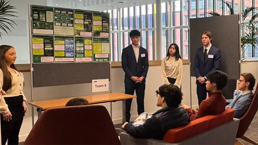 Four ITMB students presenting their poster at a showcase competition.