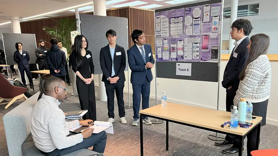 Oliver Kennet and five of his classmates presenting a poster at a showcase event at AMBS.