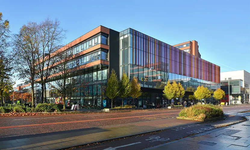 Alliance Manchester Business School building on Oxford Road at the University of Manchester, viewed from the street on a clear day.