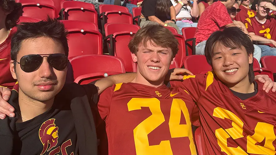 Three young men seated at an American Football match.