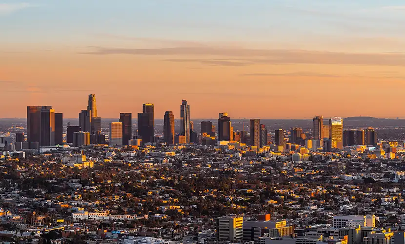 A sunset view from Griffith Park features the downtown Los Angeles skyline.